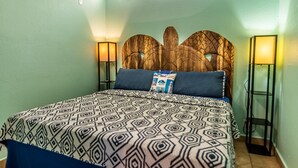 Un dormitorio con una colcha estampada, un cabecero de madera y dos lámparas de noche.