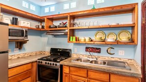 Una cocina con armarios de madera, estufa a gas, microondas y pileta.