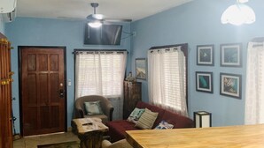 Una sala de estar con un sofá, una mesa de madera y un televisor montado en la pared.