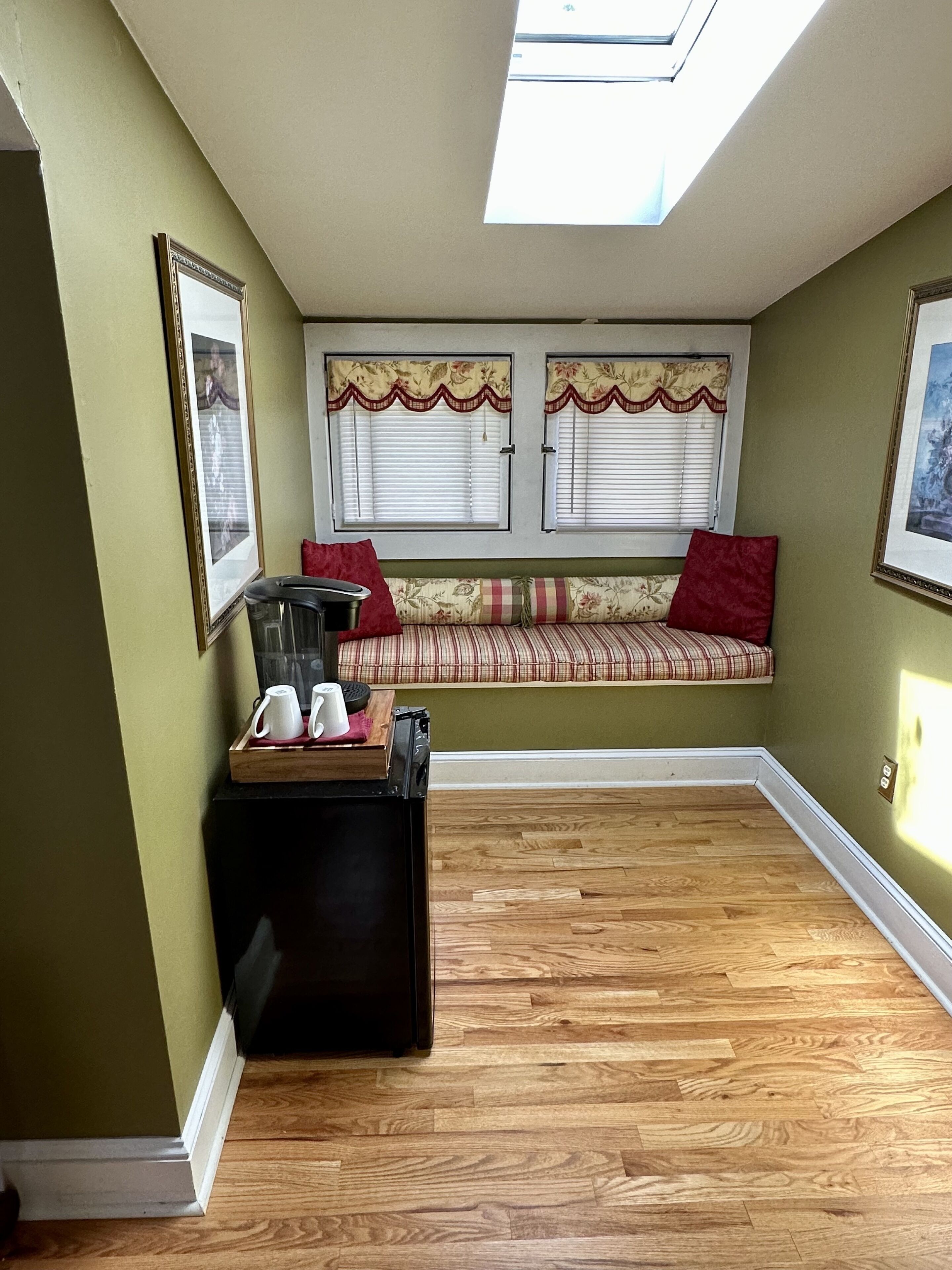 A cozy room with a built-in bench, a small table with cups and a tray, and a skylight above.
