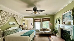 Ein Schlafzimmer mit Bett, Sessel, Kamin und Deckenventilator.