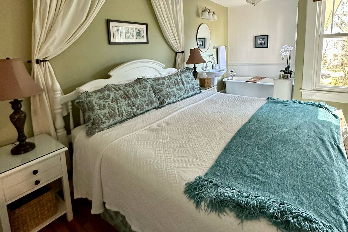 A bedroom with a bed, nightstand, lamp, and a window with curtains.