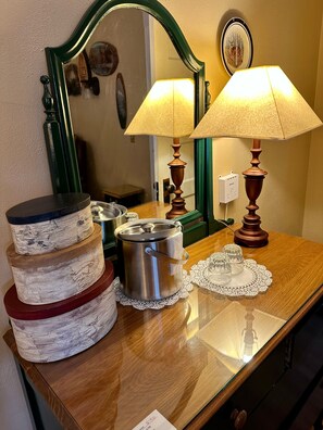 A wooden table with a stack of decorative containers, a metal pot, and a lamp.
