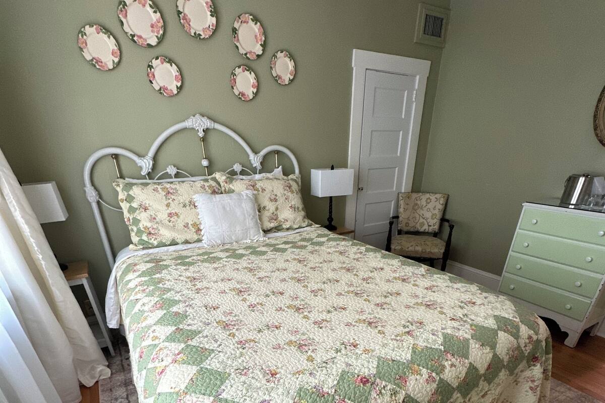 A bedroom with a bed, a dresser, a chair, and a door.