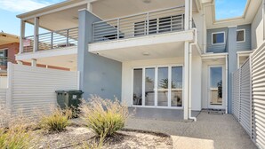 A two-story building with a balcony, large windows, and a gated entrance.