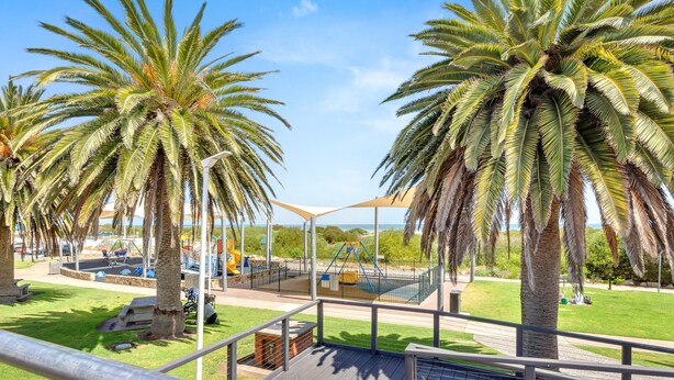 A playground with palm trees, a pool, and a covered seating area.