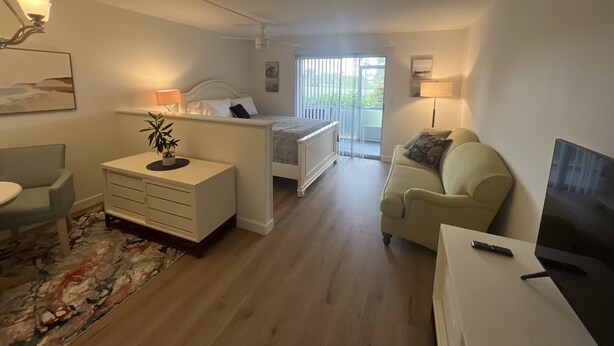 A modern living room with a bed, a sofa, a TV, and a balcony. - Cozy and sweet condo . (Fort Myers)