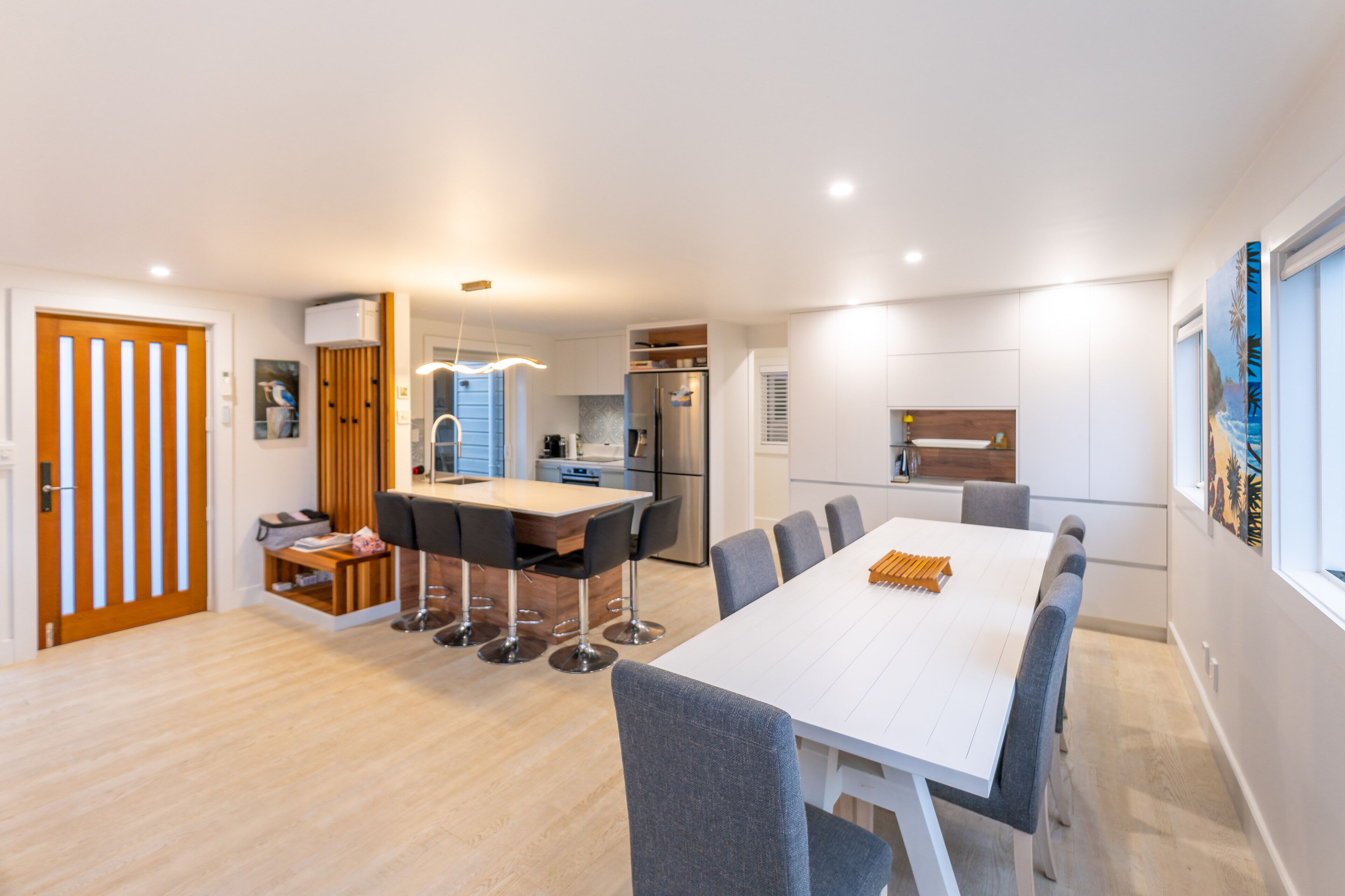 A modern kitchen with white cabinets, a built-in oven, and a refrigerator.
