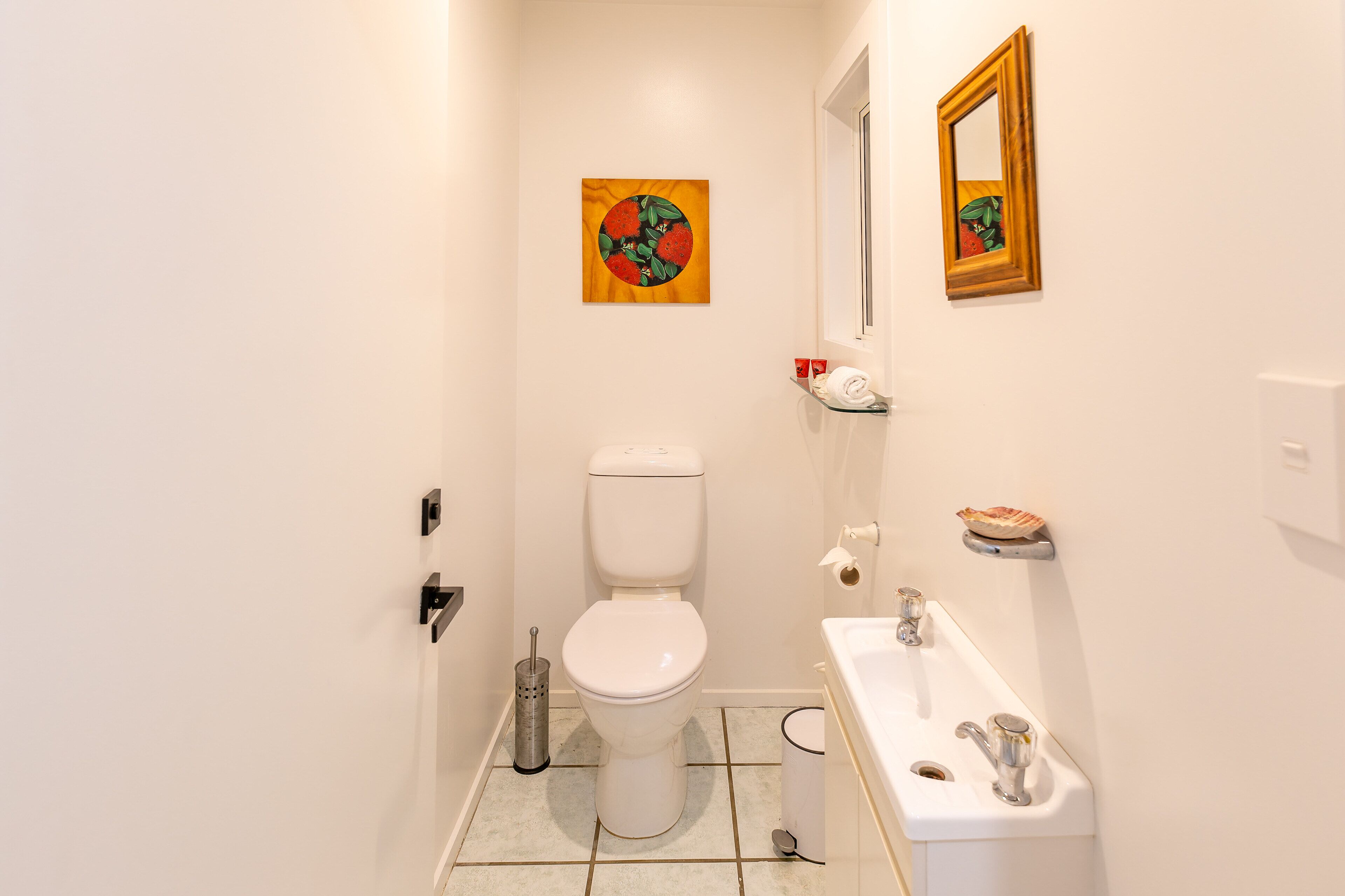 A small, clean bathroom with a toilet, sink, and a mirror.