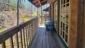 A wooden deck with a railing, a table, and two chairs. - Mountain Rose- Hot Tub, Pool Table, Firepit, Fireplace (Stanton)