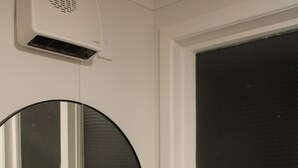 A bathroom with a white sink, black faucet, and a round mirror. There are two potted plants on the windowsill. - Orchard Leigh on the Quarry (Dunedin)
