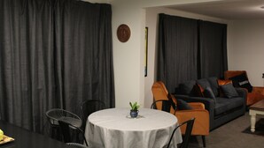 A living room with a round table, a sofa, and a dining table. - Orchard Leigh on the Quarry (Dunedin)