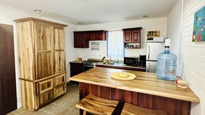 Una cocina con armarios de madera, una isla grande con taburetes, un refrigerador y un dispensador de agua.