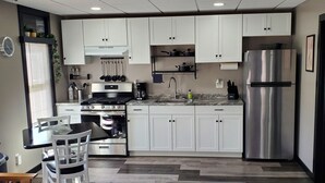 Eine moderne Küche mit weißen Schränken, einem Edelstahl-Kühlschrank und einem Essbereich mit Tisch und Stühlen.
