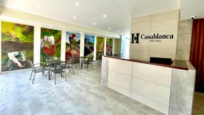 Zona de recepción de un hotel con diseño moderno, que incluye un mostrador de recepción, área de asientos y murales coloridos en las paredes.