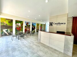 A hotel reception area with a modern design, featuring a reception desk, seating area, and colorful murals on the walls.