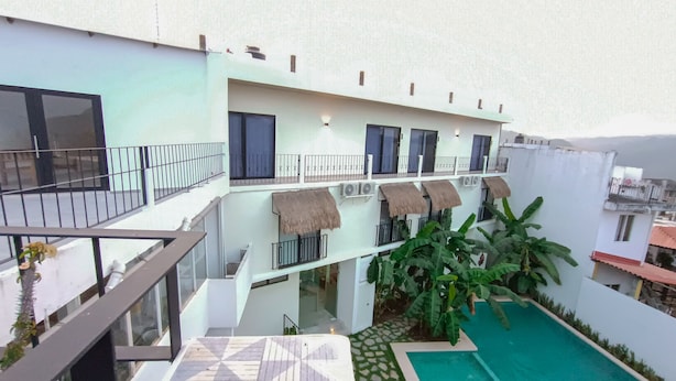 Un edificio de varios niveles con zona de piscina, que incluye una terraza estampada y una piscina pequeña con jardín alrededor.