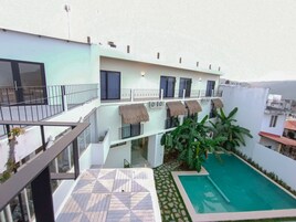 A multi-level building with a pool area, including a patterned terrace and a small pool with a surrounding garden.
