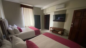 Habitación de hotel con dos camas, un televisor, un banco de madera y una puerta.