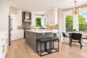 A modern kitchen with a central island, bar stools, and a dining area with a view.