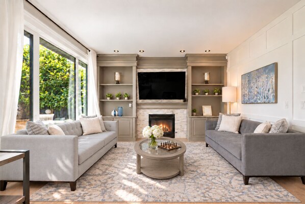A modern living room with two sofas, a fireplace, and a television.
