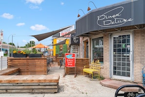 A diner with outdoor seating, a classic diner fare sign, and a storefront with a name sign.