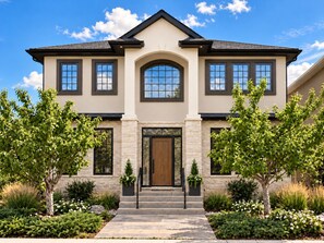 A two-story house with a symmetrical facade, a central entrance with a wooden door, and a stone base.