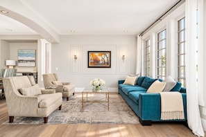 A living room with a sofa, armchairs, a coffee table, and artwork on the wall.