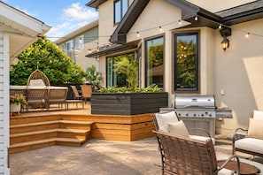 A patio with outdoor furniture, a grill, and a planter with greenery.