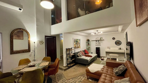 A spacious living area with a high ceiling, a dining table with chairs, a sofa, and a television. - Au Riad Des Deux Patios - Marrakech  (Marrakech)
