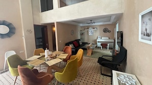 A dining area with a glass table, multiple chairs, and a piano in the background. - Au Riad Des Deux Patios - Marrakech  (Marrakech)
