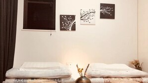 Una habitació amb dos llits, una obra d'art penjada a la paret i un ram de flors seques.