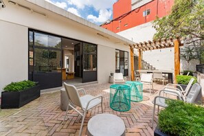 Relax in a shaded area beneath a pergola, surrounded by lush greenery and a comfortable seating arrangement.