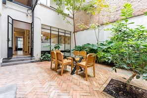 Relax in this serene courtyard with a table for four and a lush potted plant.