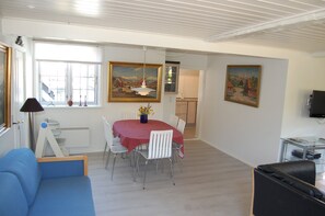 A dining area with a table, chairs, a blue sofa, and paintings on the walls.