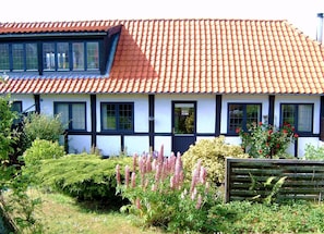 A traditional house with a red-tiled roof, white walls with black trim, and multiple windows.