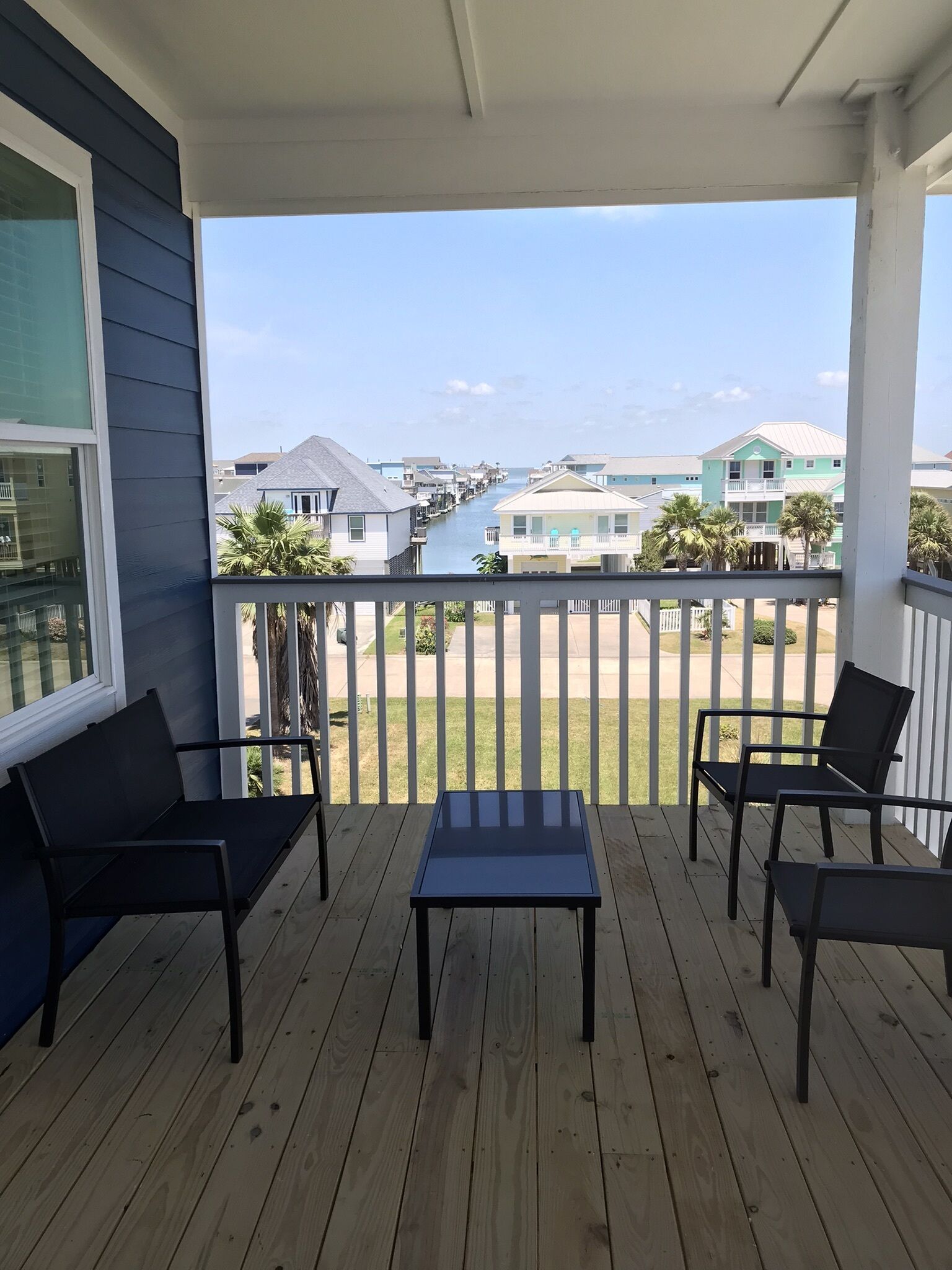 A covered porch with a view of a waterway and houses in the background.