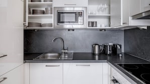 A modern kitchen with white cabinets, a stainless steel sink, a microwave, and a gas stove. - Premium Hernals 1BR w/ Balcony, nr Lidlpark, by Blueground (Vienna)
