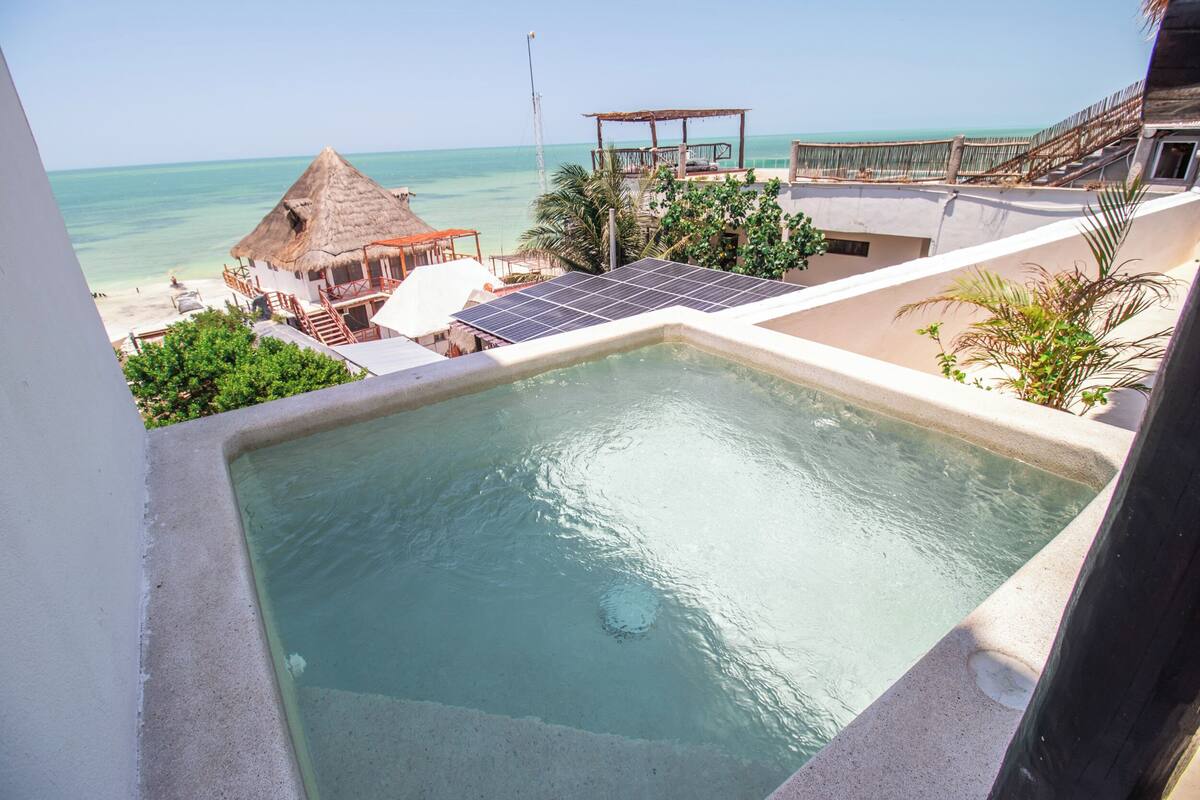 Una piscina en la azotea con vistas a la playa y al océano.
