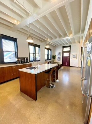 Enjoy cooking in this well-equipped kitchen with a central island, stainless steel refrigerator, and ample cabinetry.