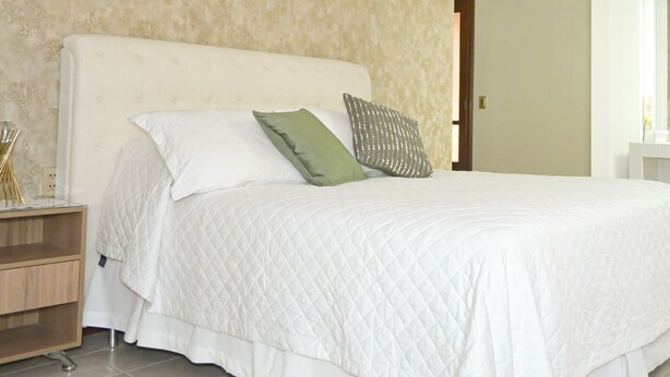 A bedroom with a large bed, a nightstand, and a hanging light fixture. - HOTEL DE SOL (Tarija)
