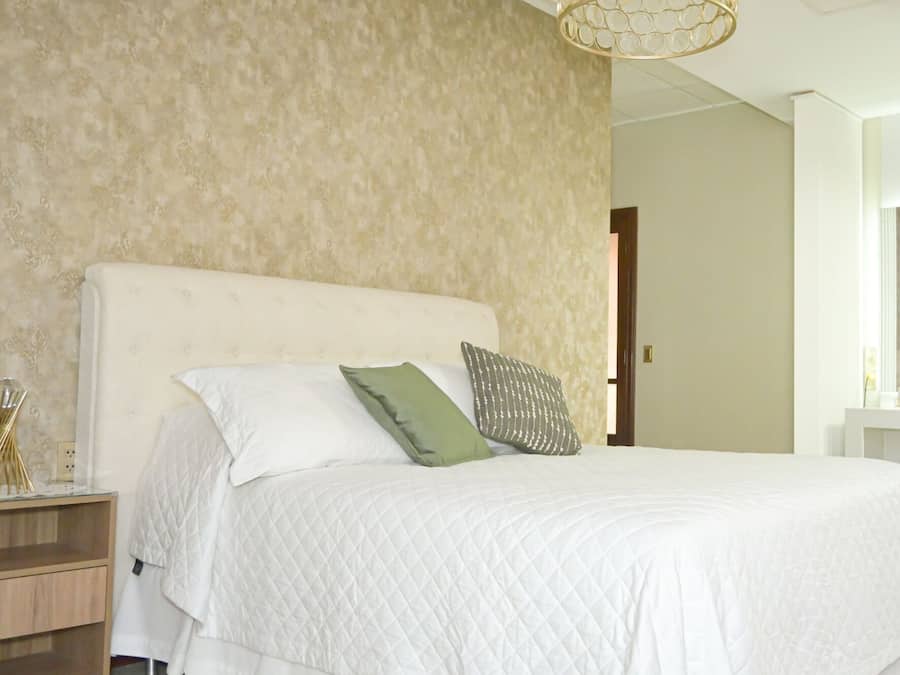 Quarto com uma cama grande, uma mesa de cabeceira e um candeeiro suspenso.