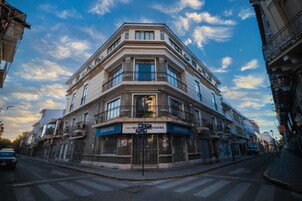 Un edificio en esquina de varios pisos, con locales comerciales en la planta baja que muestran la señalización de Samsung.
