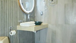 A modern bathroom with a toilet, a sink with a mirror, and a shower. - HOTEL DE SOL (Tarija)
