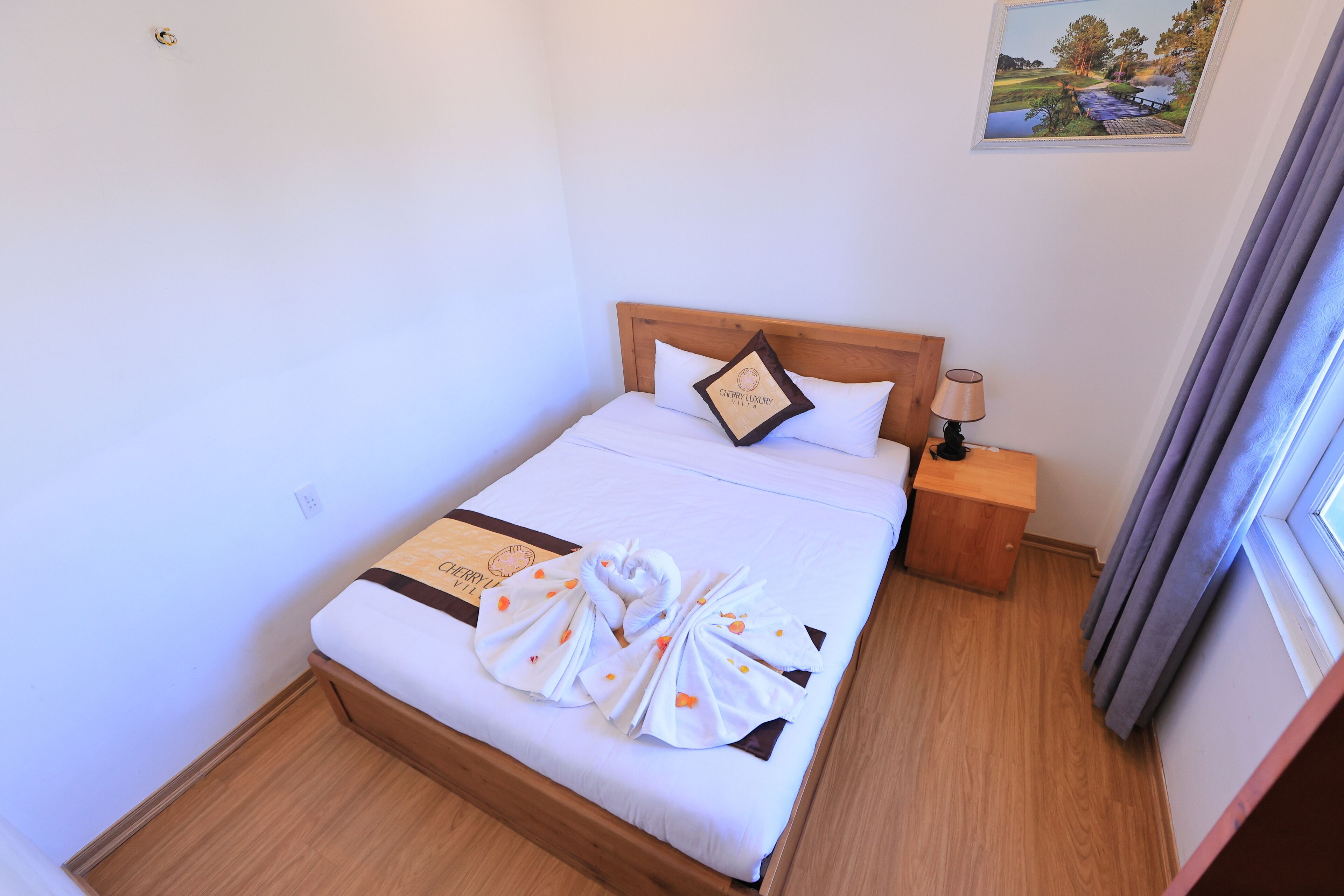 Un lit bien fait, avec une tête de lit en bois, une table de chevet avec une lampe et un tableau encadré accroché au mur.