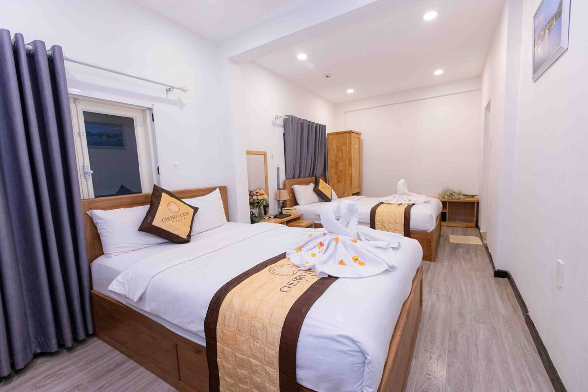 A hotel room with two beds, a wardrobe, a mirror, and a window with curtains.