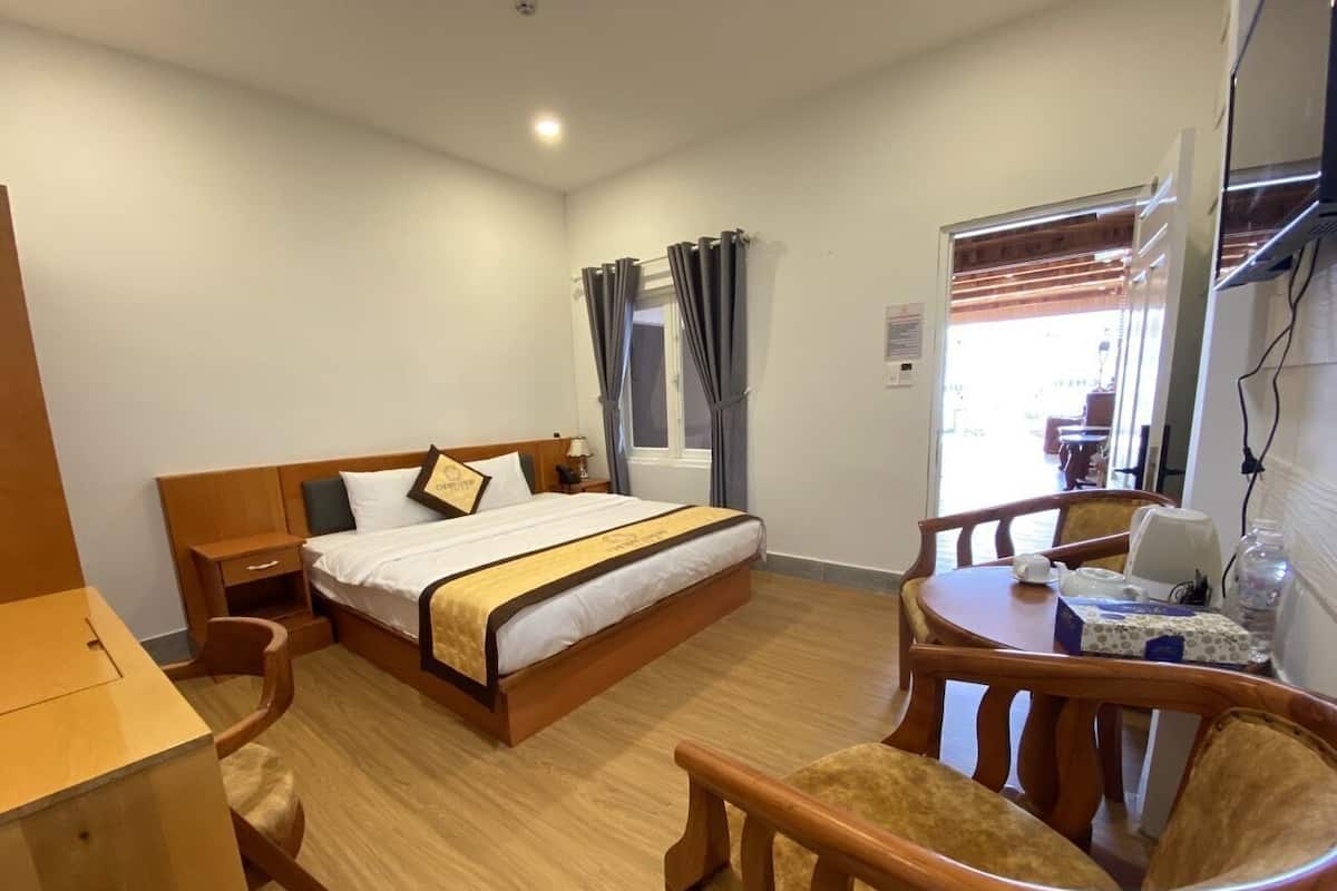 A hotel room with a bed, a desk, a chair, and a table.