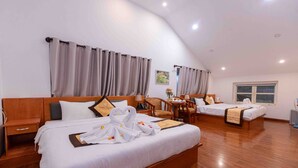 A hotel room with two beds, wooden headboards, and a dining area with a table and chairs. - Cherry Luxury Hotel (Xuan Huong - Da Lat)