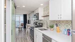 A modern kitchen with white cabinets, a stainless steel oven, and a large window.