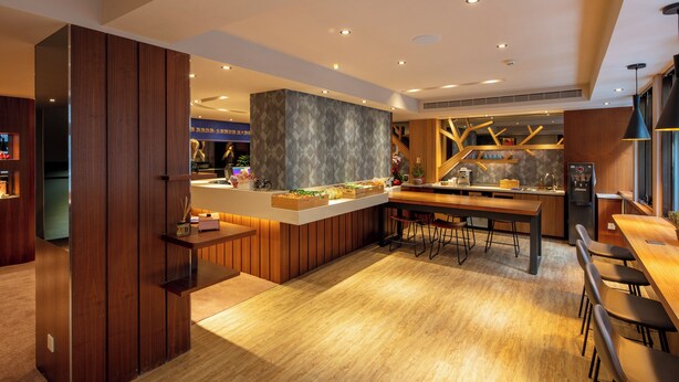 A modern kitchen with wooden cabinetry, a central island, and bar stools. - Rich & Free Hotel Kaifeng (Taipei)